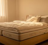 Quelles habitudes adopter chaque jour pour un sommeil de qualité ? Chambre adulte lumineuse au petit matin avec un lit soigneusement fait, du linge de lit clair et une ambiance calme et naturelle.